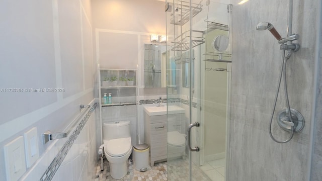 bathroom featuring tile patterned flooring, tile walls, vanity, a shower with shower door, and toilet