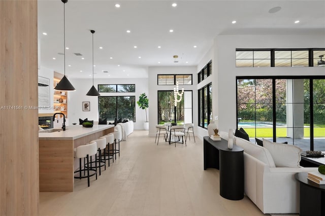 living room with sink, a notable chandelier, light hardwood / wood-style floors, and a multi sided fireplace