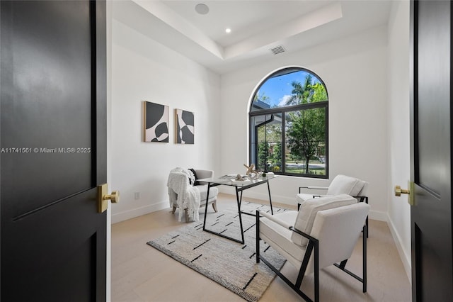 home office featuring a tray ceiling and light hardwood / wood-style floors