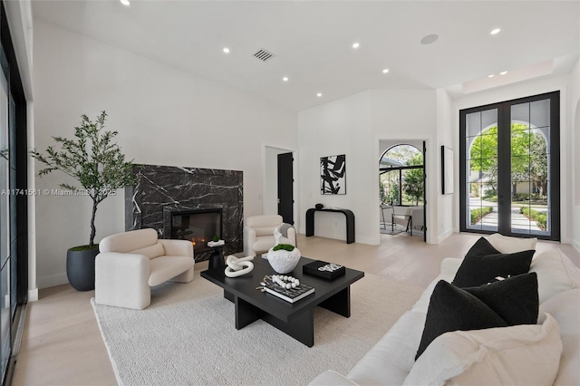 living room featuring light hardwood / wood-style floors, a fireplace, and french doors