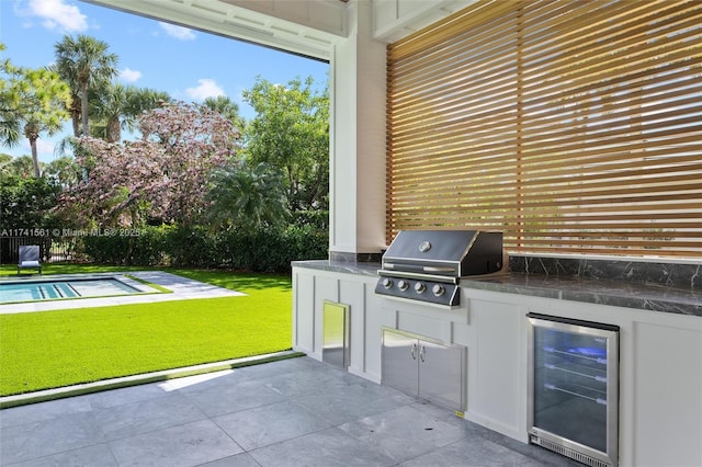 view of patio with area for grilling, a grill, beverage cooler, and a fenced in pool