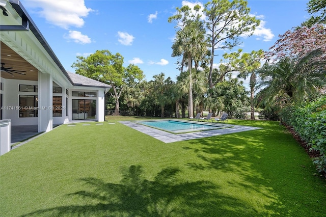 view of swimming pool with a yard and ceiling fan