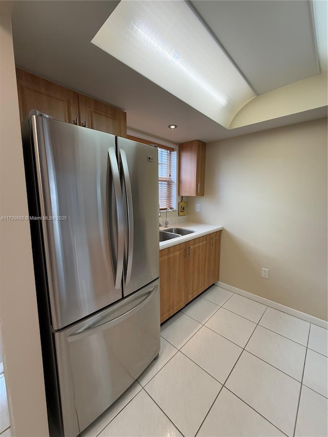 kitchen featuring sink, light tile patterned floors, and stainless steel fridge