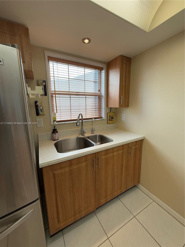 kitchen with lofted ceiling, sink, light tile patterned floors, and stainless steel refrigerator