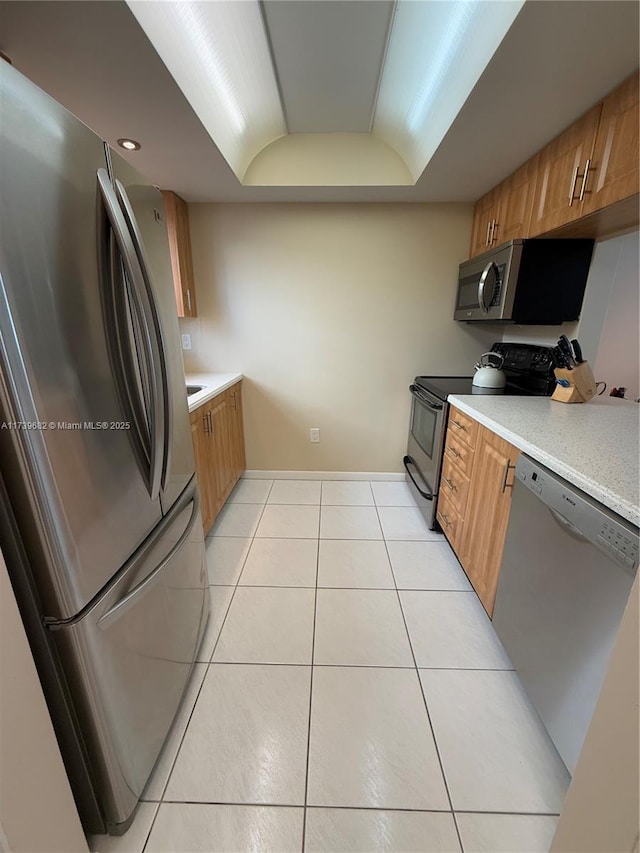 kitchen featuring a raised ceiling, appliances with stainless steel finishes, and light tile patterned floors