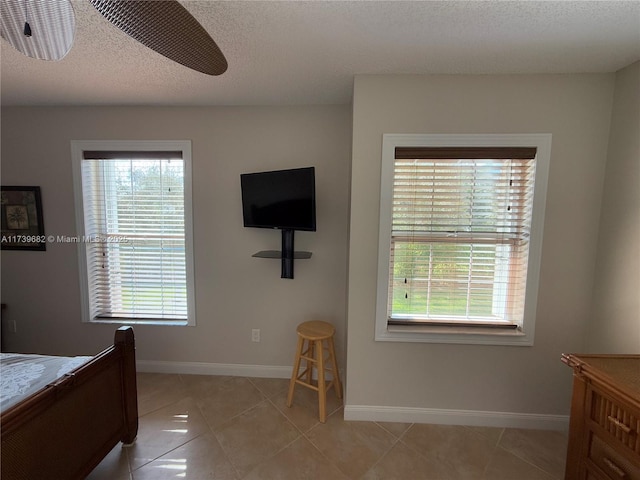 tiled bedroom featuring multiple windows and a textured ceiling