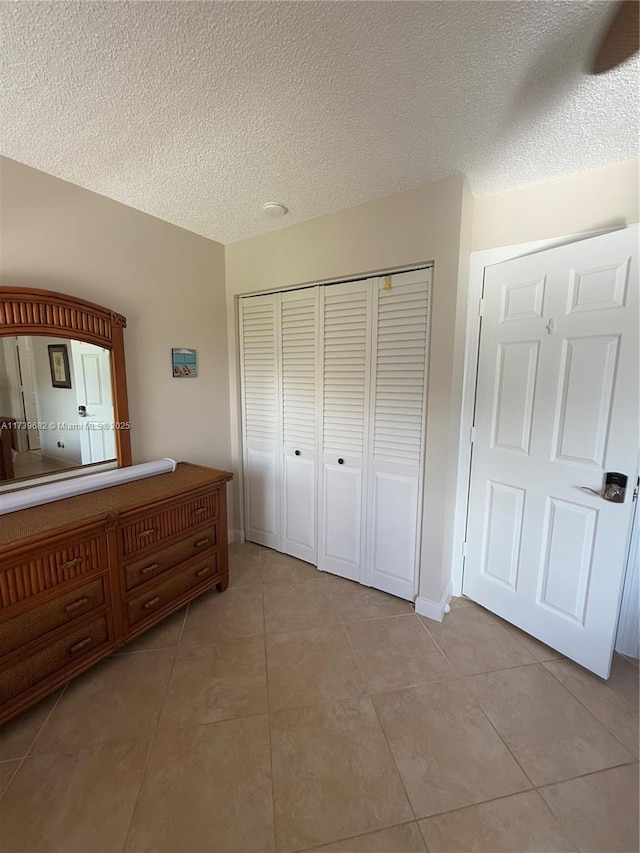 unfurnished bedroom with a closet, a textured ceiling, and light tile patterned flooring