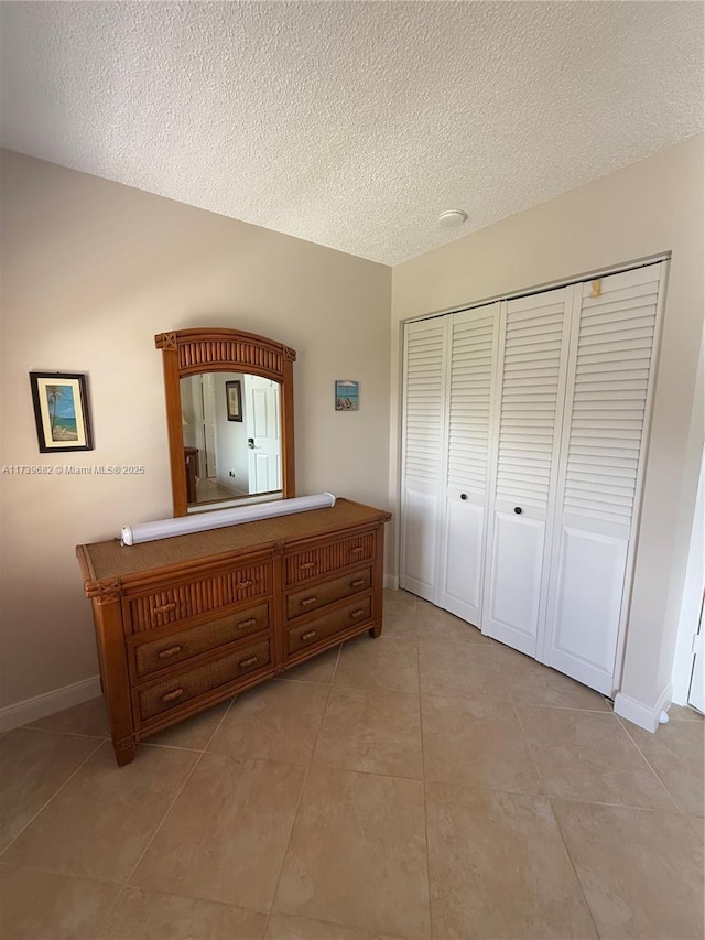 unfurnished bedroom featuring a closet, a textured ceiling, and light tile patterned floors