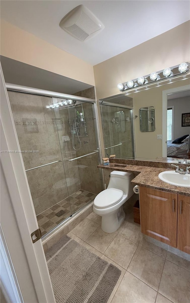 bathroom with vanity, toilet, a shower with shower door, and tile patterned flooring