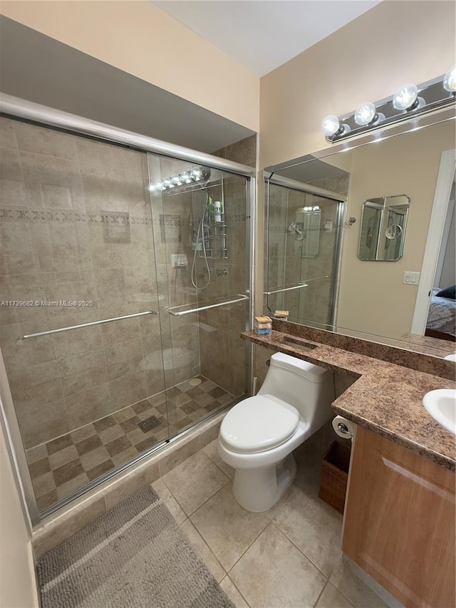 bathroom featuring vanity, a shower with door, tile patterned floors, and toilet