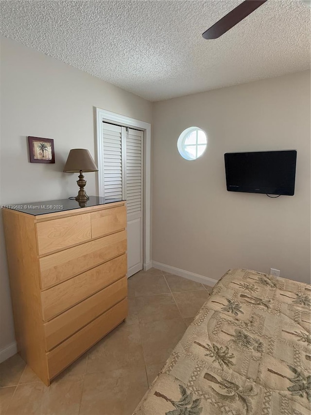 tiled bedroom featuring ceiling fan, a closet, and a textured ceiling