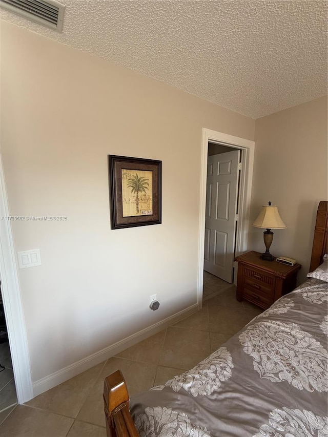 bedroom featuring light tile patterned flooring and a textured ceiling