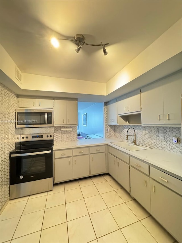 kitchen with tasteful backsplash, light tile patterned flooring, appliances with stainless steel finishes, and sink