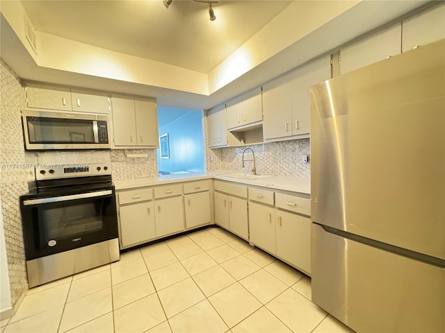 kitchen featuring light tile patterned flooring, appliances with stainless steel finishes, sink, decorative backsplash, and a tray ceiling