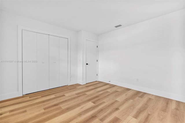 unfurnished bedroom featuring light hardwood / wood-style floors and a closet