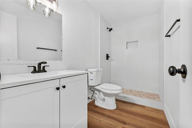 bathroom featuring vanity, hardwood / wood-style floors, a shower, and toilet