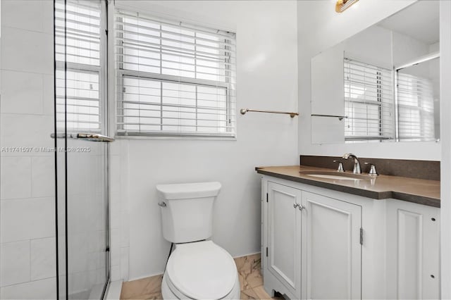 bathroom featuring vanity, a shower with shower door, and toilet