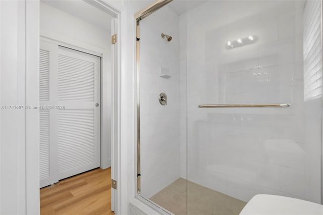 bathroom with wood-type flooring and a shower with shower door