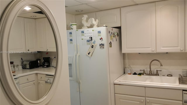 kitchen with white fridge with ice dispenser, sink, white cabinets, and decorative backsplash