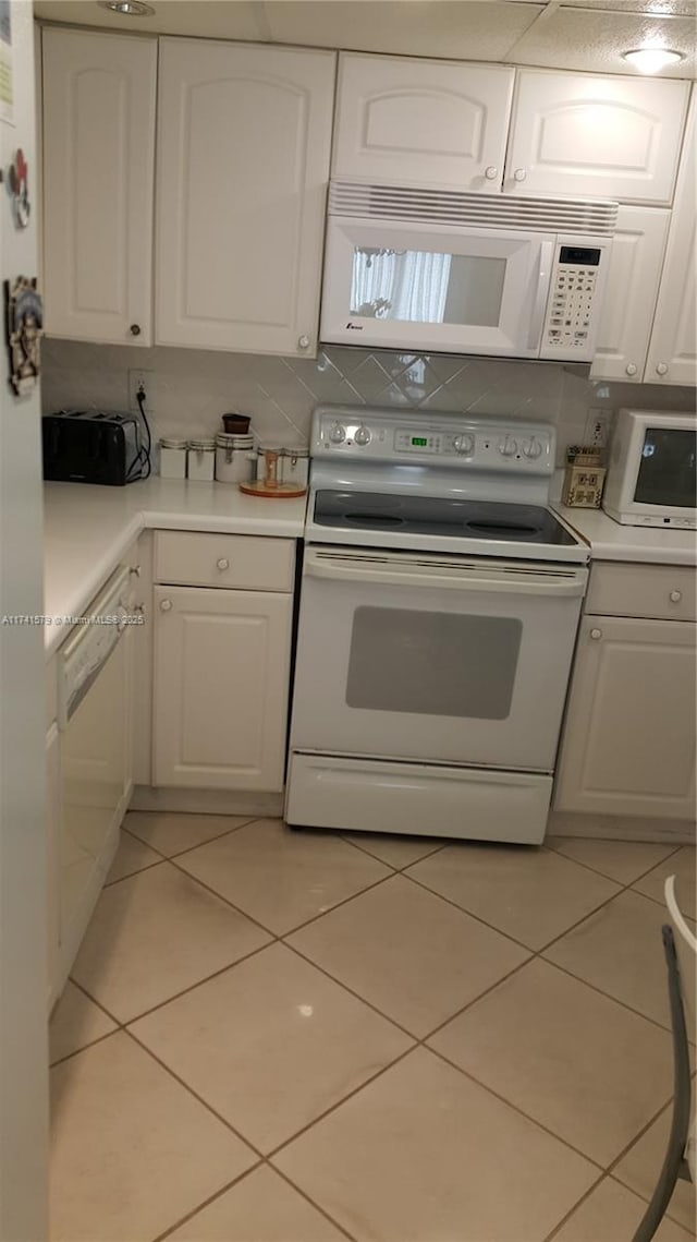 kitchen featuring white appliances, light tile patterned floors, and white cabinets