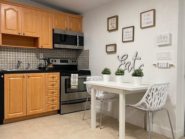 kitchen with light tile patterned flooring, sink, a breakfast bar area, tasteful backsplash, and stainless steel appliances