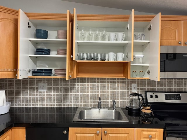 kitchen with appliances with stainless steel finishes, light brown cabinetry, sink, and backsplash