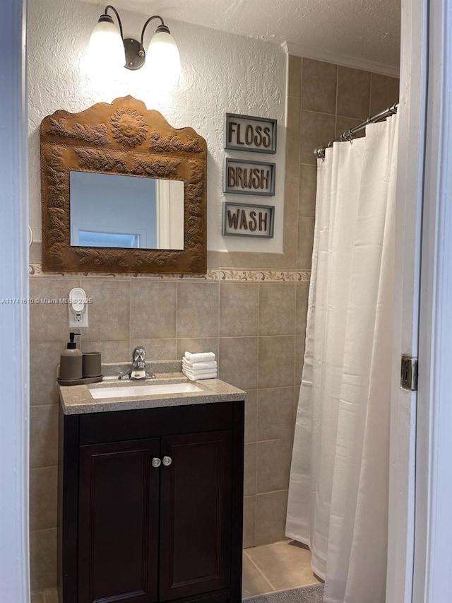 bathroom featuring tile walls, vanity, curtained shower, and a textured ceiling