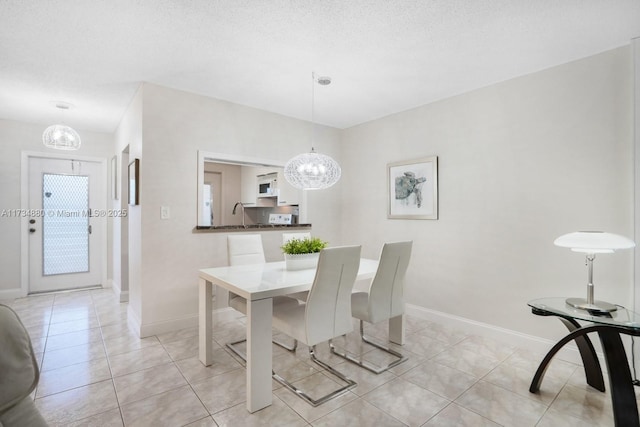 tiled dining room featuring an inviting chandelier and a textured ceiling