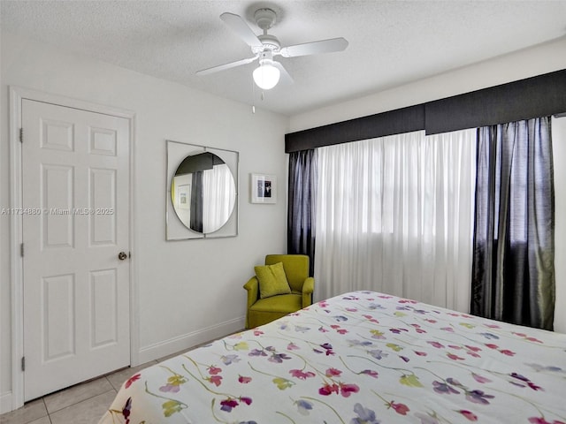 tiled bedroom with ceiling fan and a textured ceiling