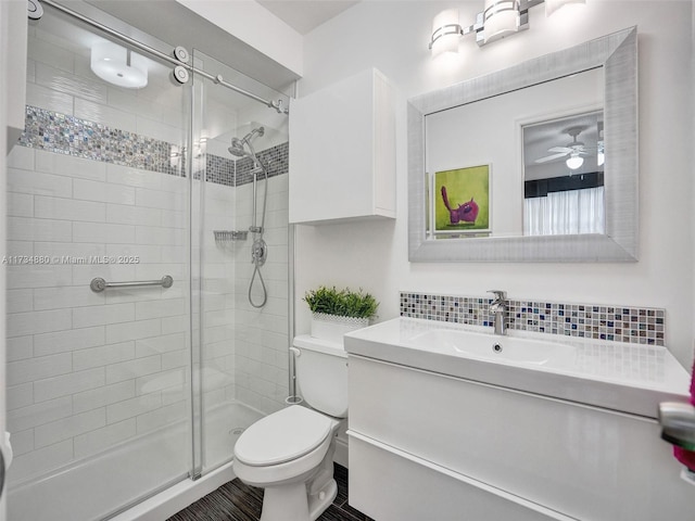 bathroom with backsplash, vanity, an enclosed shower, ceiling fan, and toilet