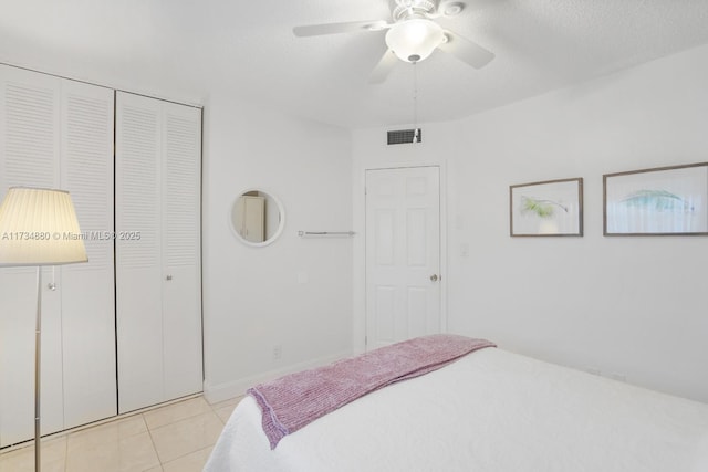 bedroom with ceiling fan, a closet, a textured ceiling, and light tile patterned floors