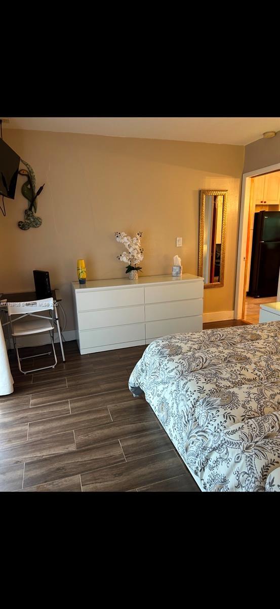 bedroom with black refrigerator and dark hardwood / wood-style flooring