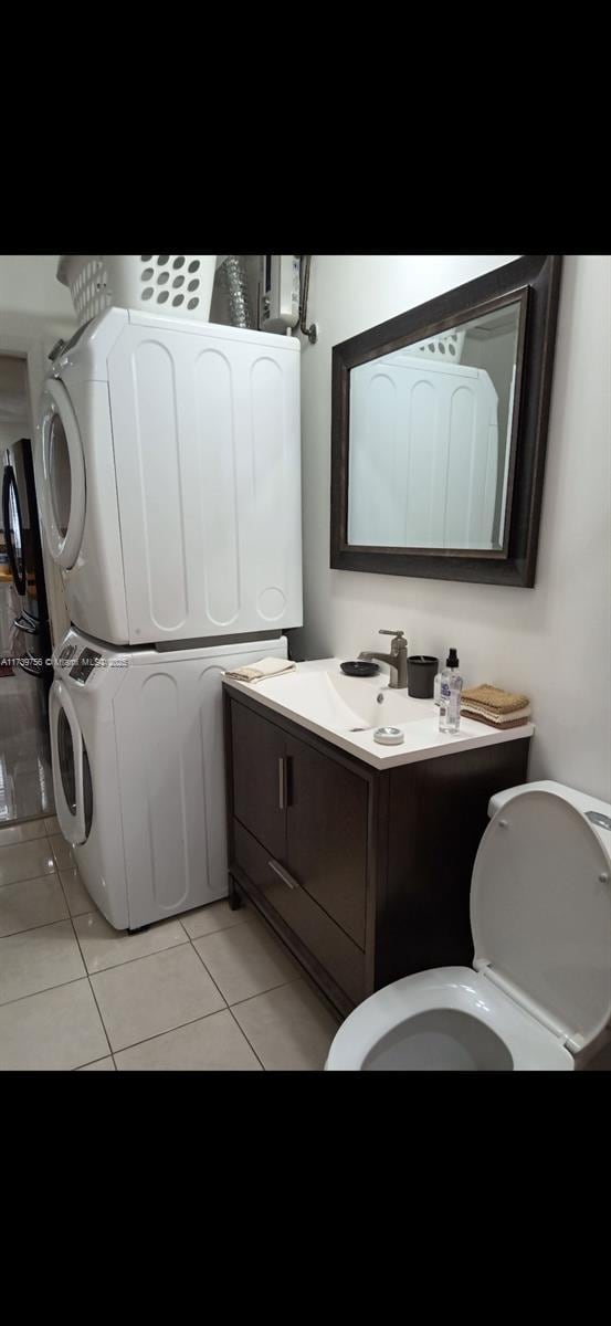 bathroom with vanity, tile patterned floors, toilet, and stacked washer / dryer