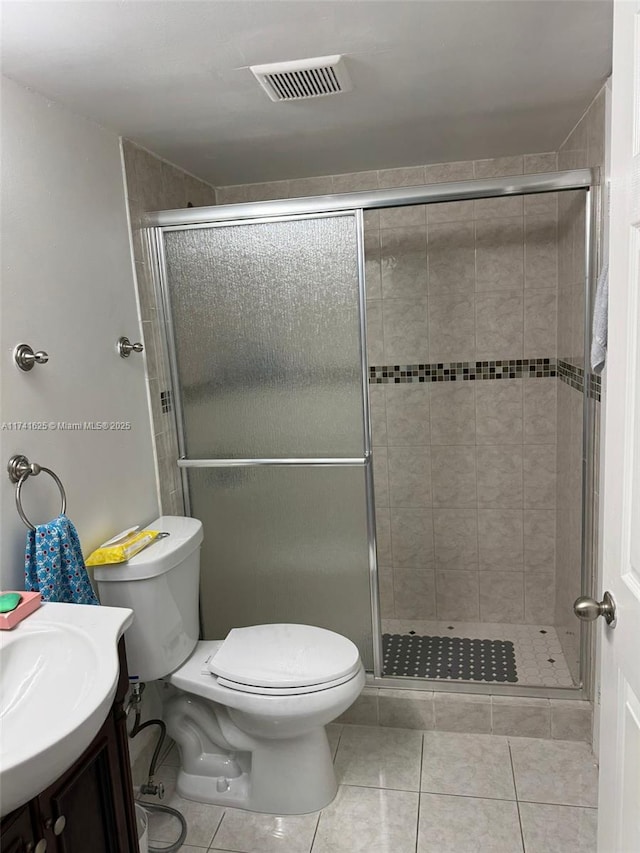 bathroom with tile patterned flooring, vanity, a shower with door, and toilet