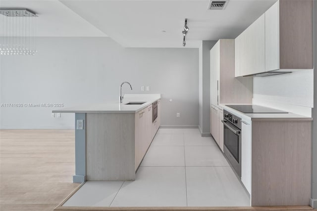 kitchen featuring visible vents, oven, a peninsula, black electric stovetop, and a sink