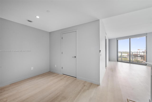 unfurnished bedroom with baseboards, visible vents, wood finished floors, floor to ceiling windows, and recessed lighting