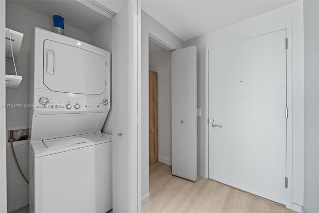 laundry area with light wood-style floors, laundry area, and stacked washing maching and dryer