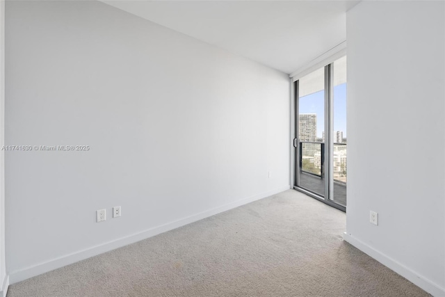 carpeted spare room featuring baseboards, a wall of windows, and a city view