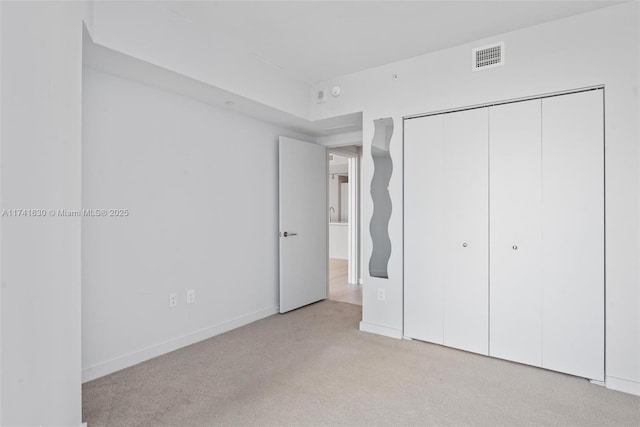 unfurnished bedroom featuring carpet floors, a closet, visible vents, and baseboards