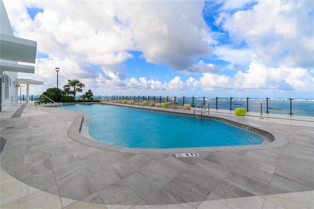 view of swimming pool with a patio area and a water view