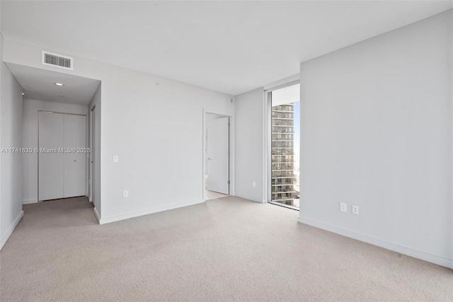 empty room featuring expansive windows, carpet flooring, visible vents, and baseboards