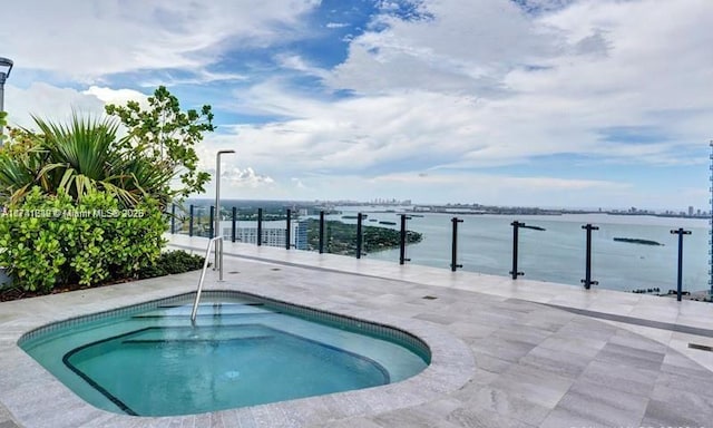 view of pool featuring a hot tub, a patio, and a water view