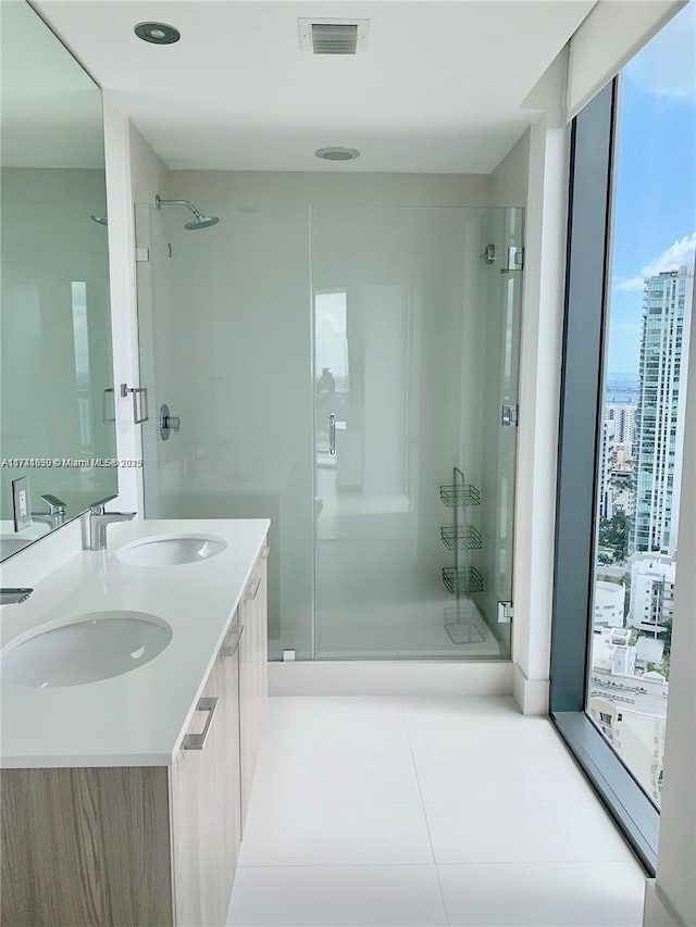 bathroom featuring a shower with door, vanity, tile patterned flooring, and a wall of windows