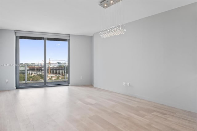 empty room featuring baseboards, wood finished floors, and floor to ceiling windows