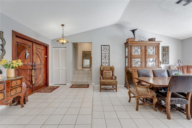 tiled dining room featuring vaulted ceiling and a textured ceiling