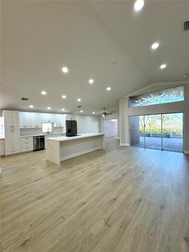 kitchen featuring light wood finished floors, a kitchen island, open floor plan, dishwashing machine, and black refrigerator with ice dispenser