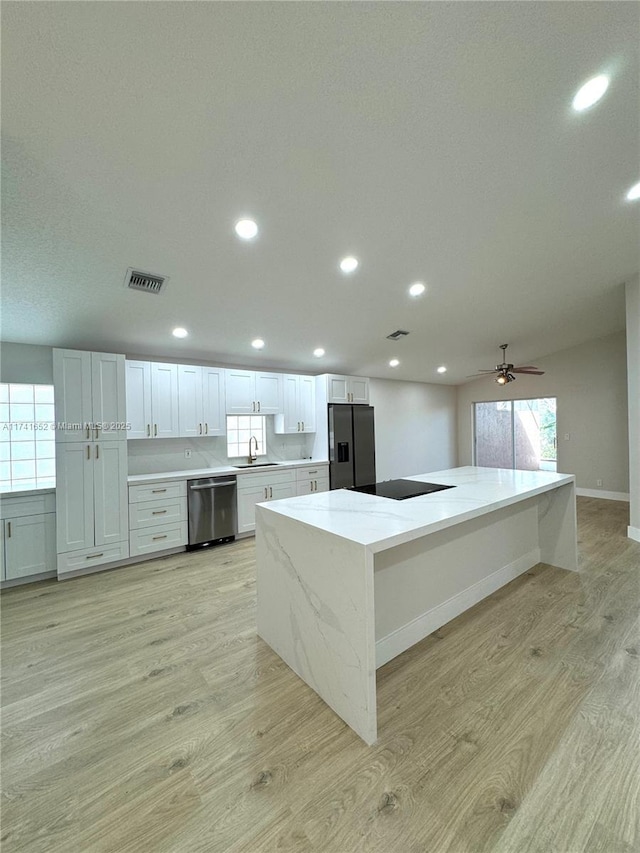 kitchen featuring light wood finished floors, visible vents, dishwasher, fridge with ice dispenser, and a sink