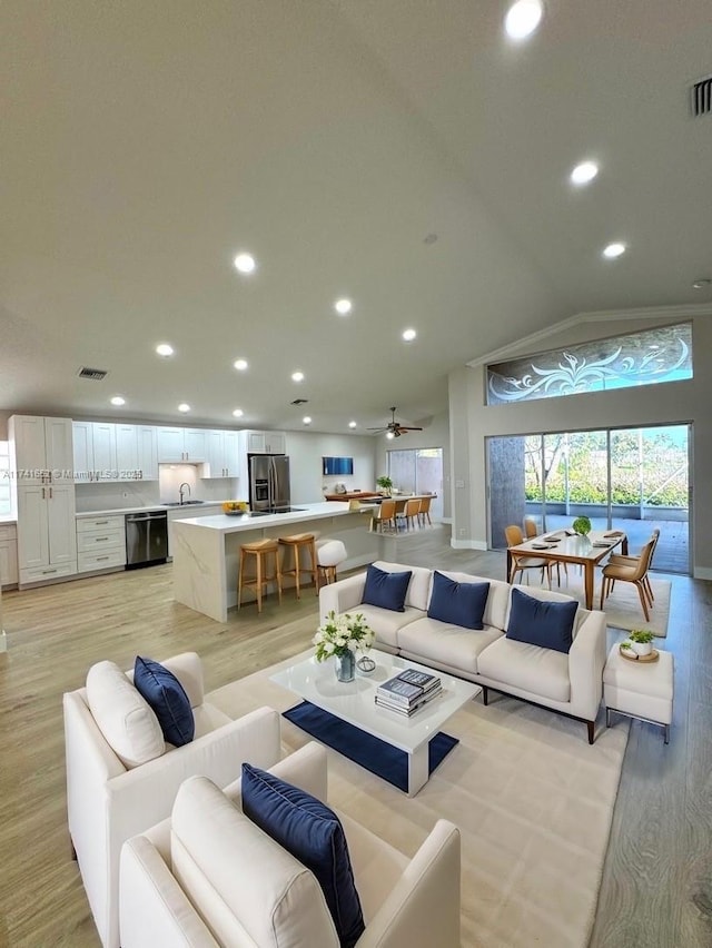 living room with visible vents, light wood-style flooring, a ceiling fan, recessed lighting, and lofted ceiling