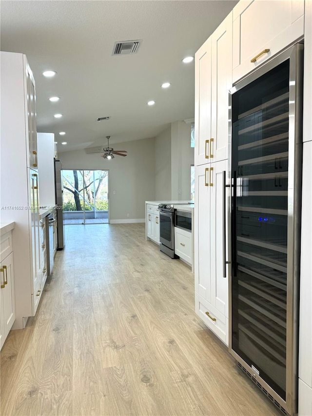 kitchen featuring light wood finished floors, visible vents, wine cooler, appliances with stainless steel finishes, and white cabinets
