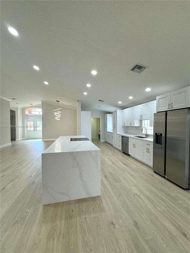 kitchen featuring visible vents, a sink, stainless steel appliances, white cabinets, and light wood-type flooring